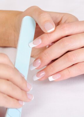 manicurist-doing-polishing-female-fingernails-with-french-manicure